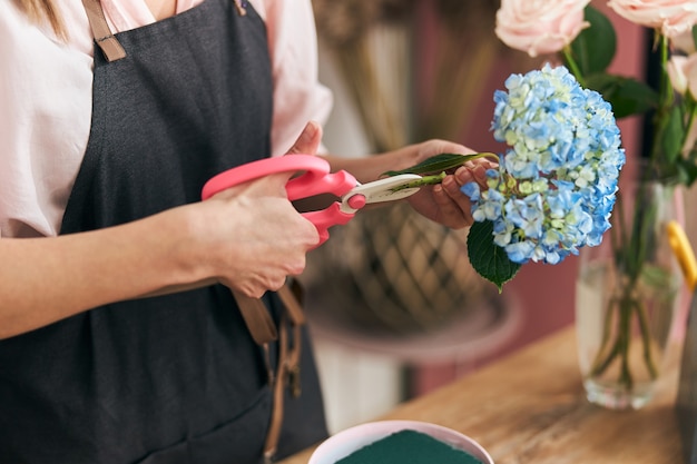 Floristería profesional joven haciendo ramos de flores en la tienda de flores