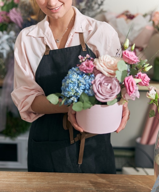 Floristería profesional joven haciendo ramos de flores en la tienda de flores