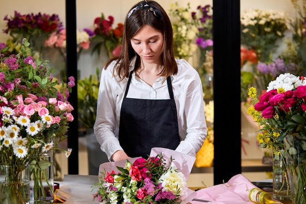 Floristería profesional trabaja con colores. Vendedor de flores elige flores para ramo futuro