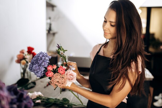 Floristería recoge un ramo de rosas frescas, hortensias azules y otras flores en la florería.