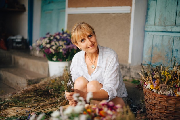 la floristería se sienta en el campo en medio de una cosecha de flores y crea con las manos un hermoso ramo