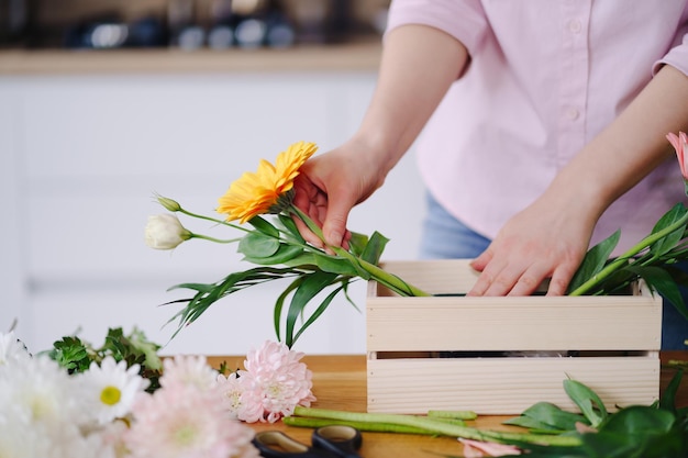 Floristería en el trabajo joven mujer morena manos haciendo moda composición moderna de diferentes flores en casa