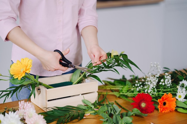 Floristin bei der Arbeit junge brünette Frau Hände machen Mode moderne Komposition aus verschiedenen Blumen zu Hause