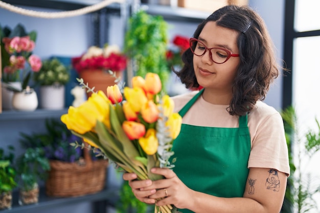 Floristin der jungen Frau, die selbstbewusst lächelt, bereitet Blumenstrauß beim Floristen vor