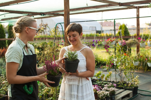 Floristin, die dem Kunden im Blumenladen Blumen zeigt