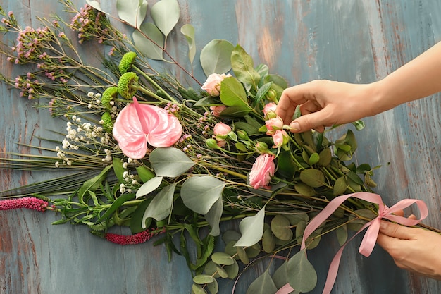 Floristin, die einen schönen Blumenstrauß auf dem Tisch zubereitet