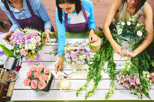 Floristin mit drei Mädchen, die mit Blumen arbeitet