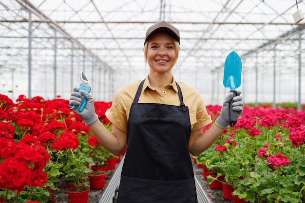 Floristin mit Pruner und Gartenhandkelle im Gewächshaus