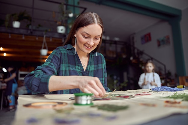 Flourist Shop mit verschiedenen Arten von getrockneten Blumen. Junge glückliche selbstbewusste Spezialistin arbeitet mit ihrem weiblichen Kind.