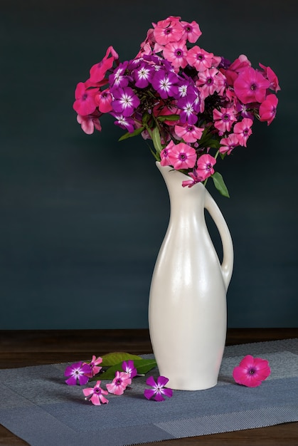 Floxes lindos em um vaso de cerâmica branca em uma mesa de madeira flores