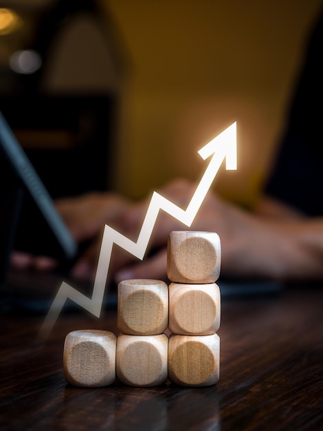 Fluctuación flecha en zigzag que se eleva en bloques de cubo de madera como pasos de gráfico mientras el empresario trabaja con una computadora portátil Objetivo de crecimiento del mercado de negocios y éxito Progreso y conceptos de gestión