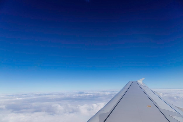 Flügel des Flugzeugs über den Wolken in der Himmelsansicht vom Fenster