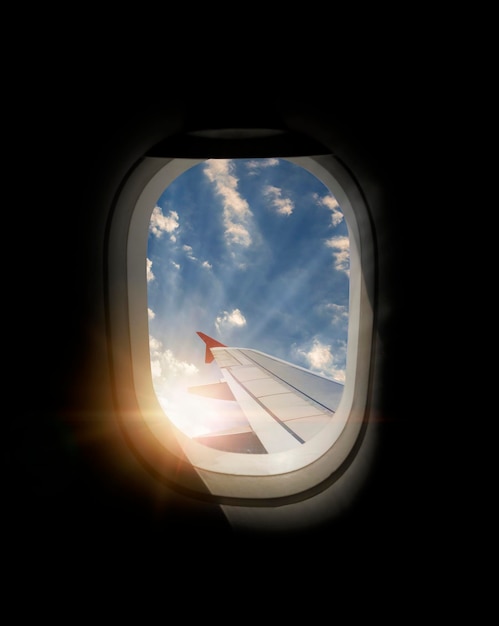 Flügel eines Flugzeugs, das über der Stadt fliegt Der Blick aus einem Flugzeugfenster Bewölkter und farbiger Himmel mit Sonnenlicht