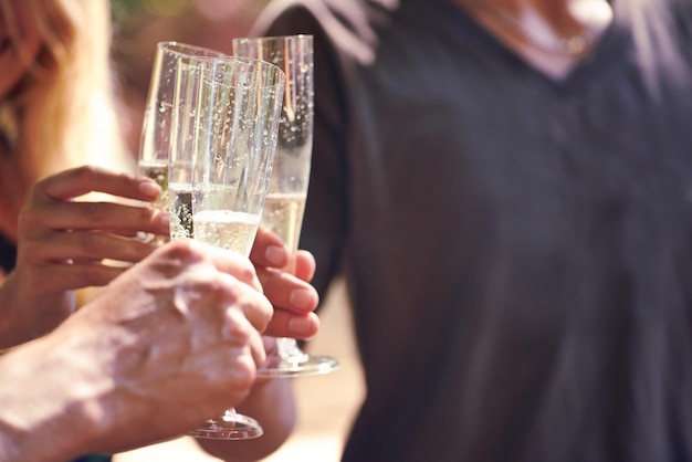 Flüssiges Funkeln Schnappschuss von Menschen, die zusammen Champagner im Freien trinken