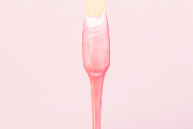 Flüssiges Wachs für die rosa Enthaarung läuft vom Stick ab.
