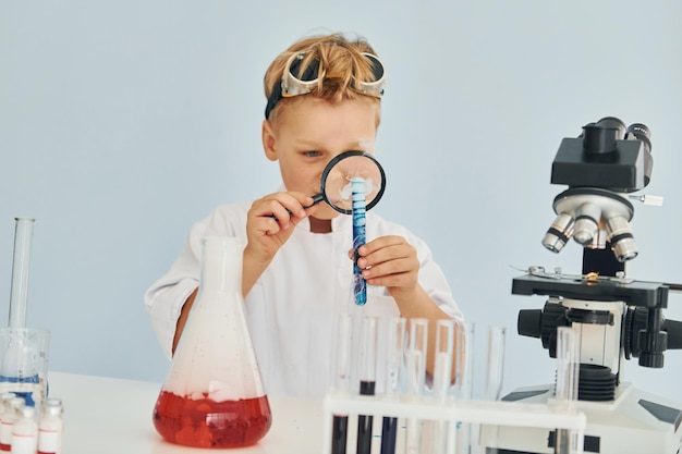 Flüssigkeit im Reagenzglas genau betrachten Kinder in weißen Kitteln spielen einen Wissenschaftler im Labor, indem sie Geräte verwenden