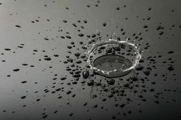 Foto flüssigkeits- oder wassertropfen spritzen auf dem schwarzen boden, abstrakter hintergrund