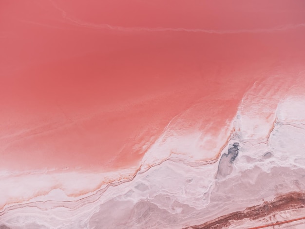 Flug über einen rosafarbenen Salzsee Salzproduktionsanlagen saline Verdunstungsteich Felder im salzigen See Dunaliella salina verleihen einem mineralischen See mit trockener kristallisierter salziger Küste ein rotrosa Wasser