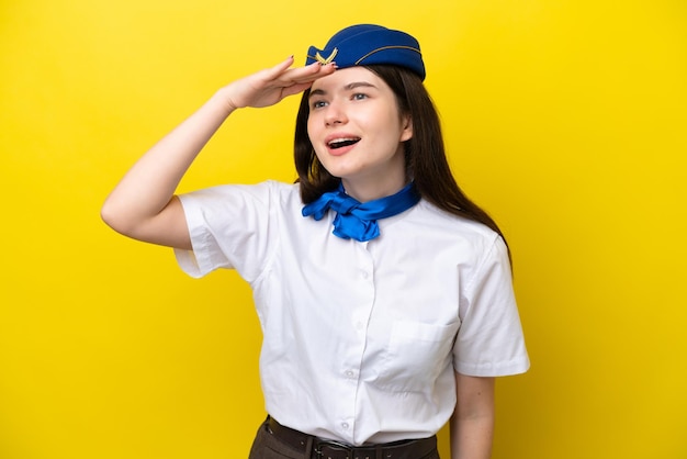 Flugbegleiterin Russische Frau isoliert auf gelbem Hintergrund, die mit der Hand weit wegschaut, um etwas zu sehen