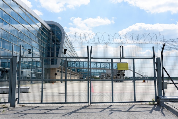 Flughafenzaungitter auf dem Hintergrund der Passagierbrücken zum Einsteigen der Passagiere. Für den Test auf die Platte legen.