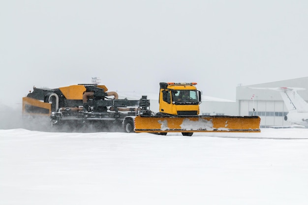 Flugplatz-Schneefräsen reinigen den Bereich in der Nähe des Flugzeughangars am Flughafen in einem schweren Schneesturm