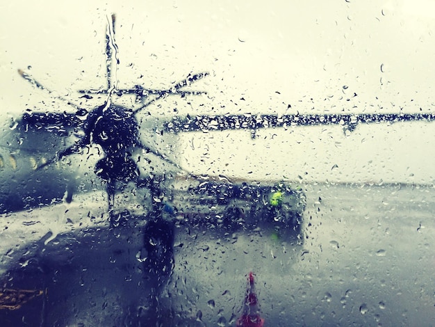 Flugzeug auf der Start- und Landebahn, gesehen durch ein nasses Glasfenster während des Monsuns
