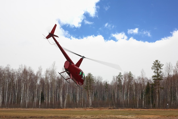 Flugzeug der kleine rote Hubschrauber auf bewölktem Himmelshintergrund