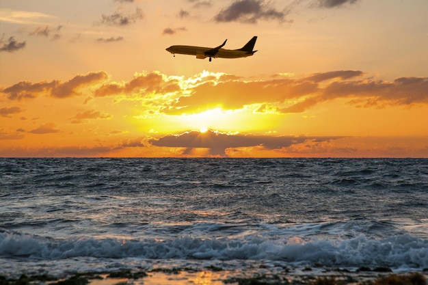Flugzeug fliegt bei Sonnenuntergang über das Meer Sonne scheint durch die Wolken