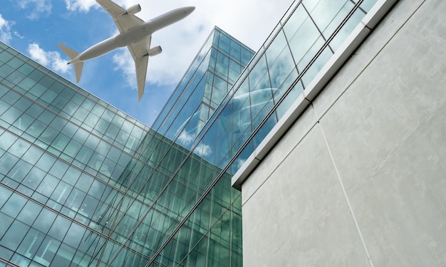 Flugzeug fliegt über einem modernen Bürogebäude. Außenfassade eines Wolkenkratzers aus grünem Glas