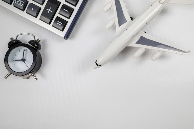 Flugzeug Spielzeug mit Wecker und Taschenrechner, isoliert auf weiss Flugzeit Das Konzept der Kosten für Flugtickets steigende Preise für Flugreisen