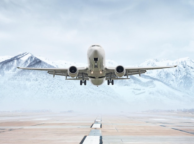 Flugzeug startet von der Landebahn des Flughafens vor der Kulisse malerischer schneebedeckter Berge