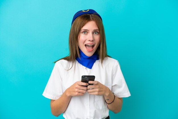 Flugzeug Stewardess Engländerin isoliert auf blauem Hintergrund überrascht und sendet eine Nachricht