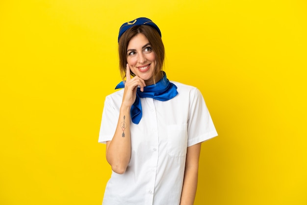 Flugzeug-Stewardess-Frau isoliert auf gelbem Hintergrund, die eine Idee denkt, während sie nach oben schaut
