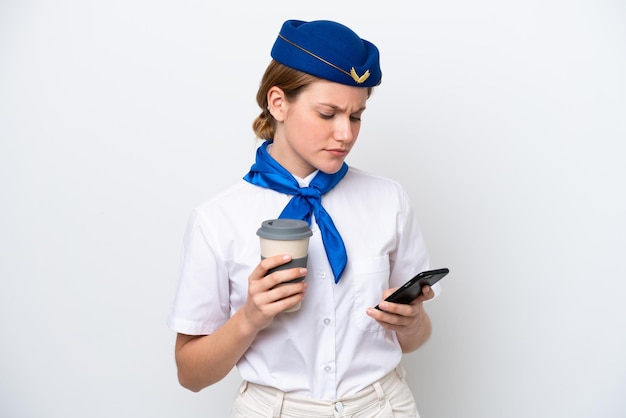 Flugzeug Stewardess Frau isoliert auf weißem Hintergrund hält Kaffee zum Mitnehmen und ein Handy