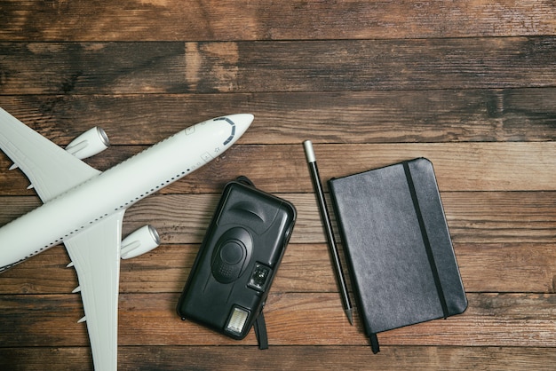 Flugzeuge mit einem Notizbuch und einer Kamera auf einem hölzernen Hintergrund