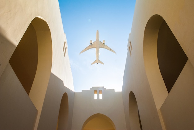 Flugzeuge über dem arabischen Hof des Hauses mit weißen Wänden und klarem blauem Himmel