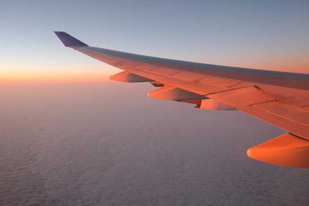 Flugzeugfensteransicht bei Sonnenuntergang für Ferienkonzept