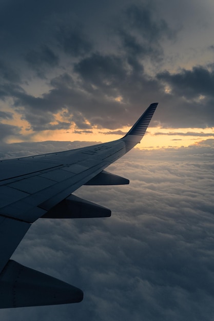 Flugzeugflügel fliegt bei Sonnenuntergang über Wolken