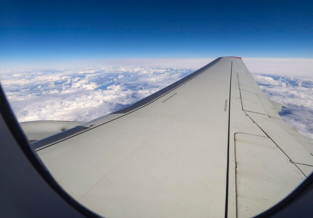 Flugzeugflügel im Flug unter den Wolken über der Stadt Moskau in Russland