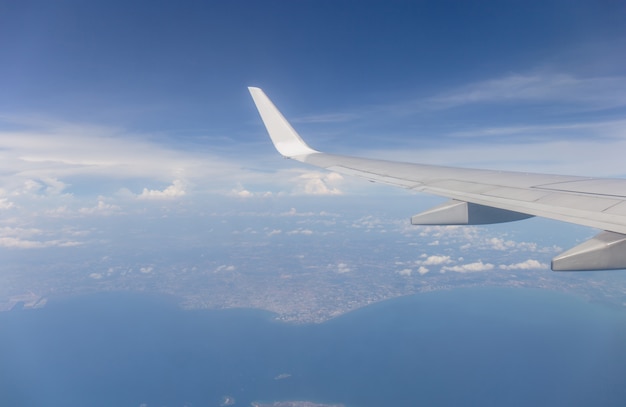 Flugzeugflügelansicht aus dem Fenster heraus der Hintergrund des bewölkten Himmels