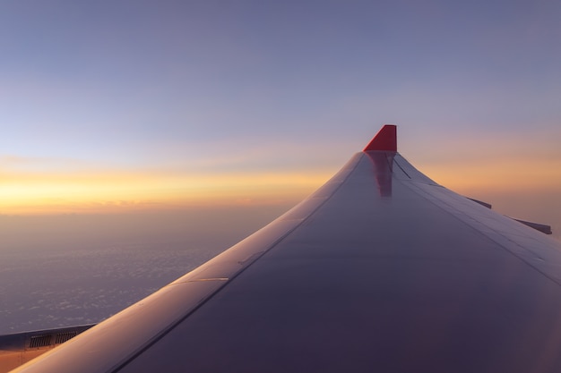 Flugzeugflügelfliegen über Wolkensonnenaufgang