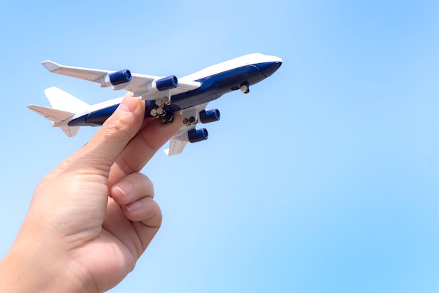 Flugzeugmodell in der Hand auf sonnigem Himmel. Konzepte von Reisen, Transport