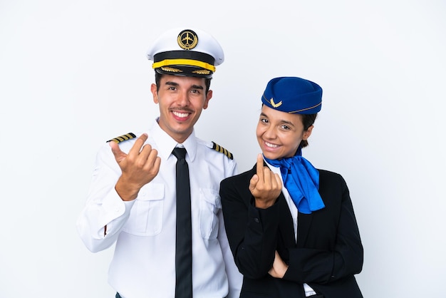 Flugzeugpilot und Mixed Race Stewardess isoliert auf weißem Hintergrund, die einladen, mit der Hand zu kommen. Schön, dass du gekommen bist