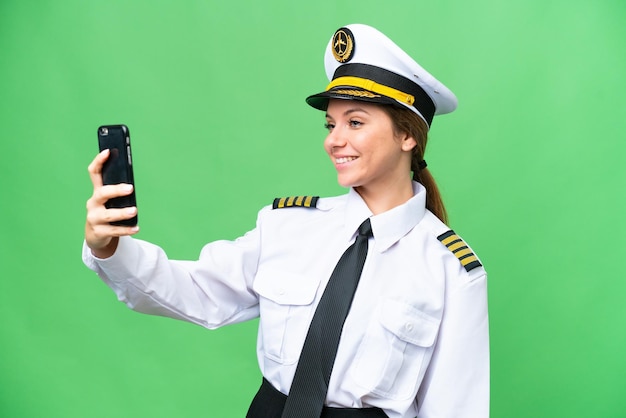 Flugzeugpilotin über isoliertem Chroma-Key-Hintergrund, die ein Selfie macht