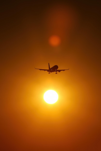 Flugzeugsilhouette im orangefarbenen Himmel des Sonnenuntergangs