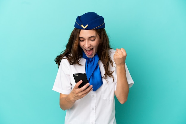 Flugzeugstewardess Frau isoliert auf blauem Hintergrund überrascht und sendet eine Nachricht