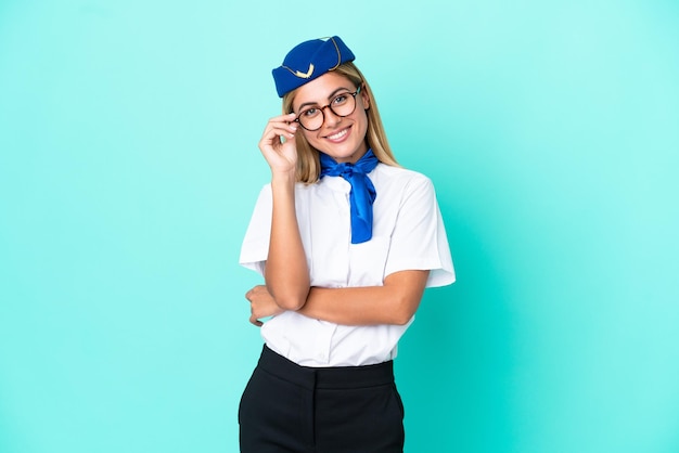 Flugzeugstewardess uruguayische Frau auf blauem Hintergrund mit Brille isoliert und glücklich