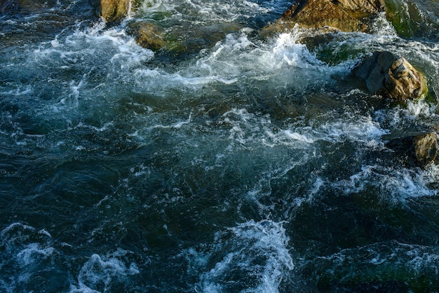 Fluir para um rio tempestuoso entre as rochas no parque outono em um dia quente