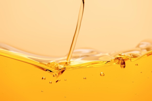 Flujo de líquido amarillo brillante con salpicaduras y burbujas aisladas en amarillo