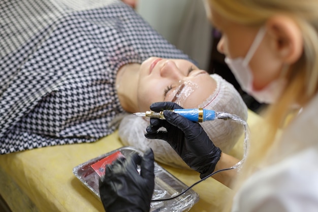 El flujo de trabajo de las cejas microblading en un salón de belleza. Mujer que tiene sus cejas teñidas. Maquillaje semipermanente para cejas. Centrarse en la cara y la ceja de la modelo